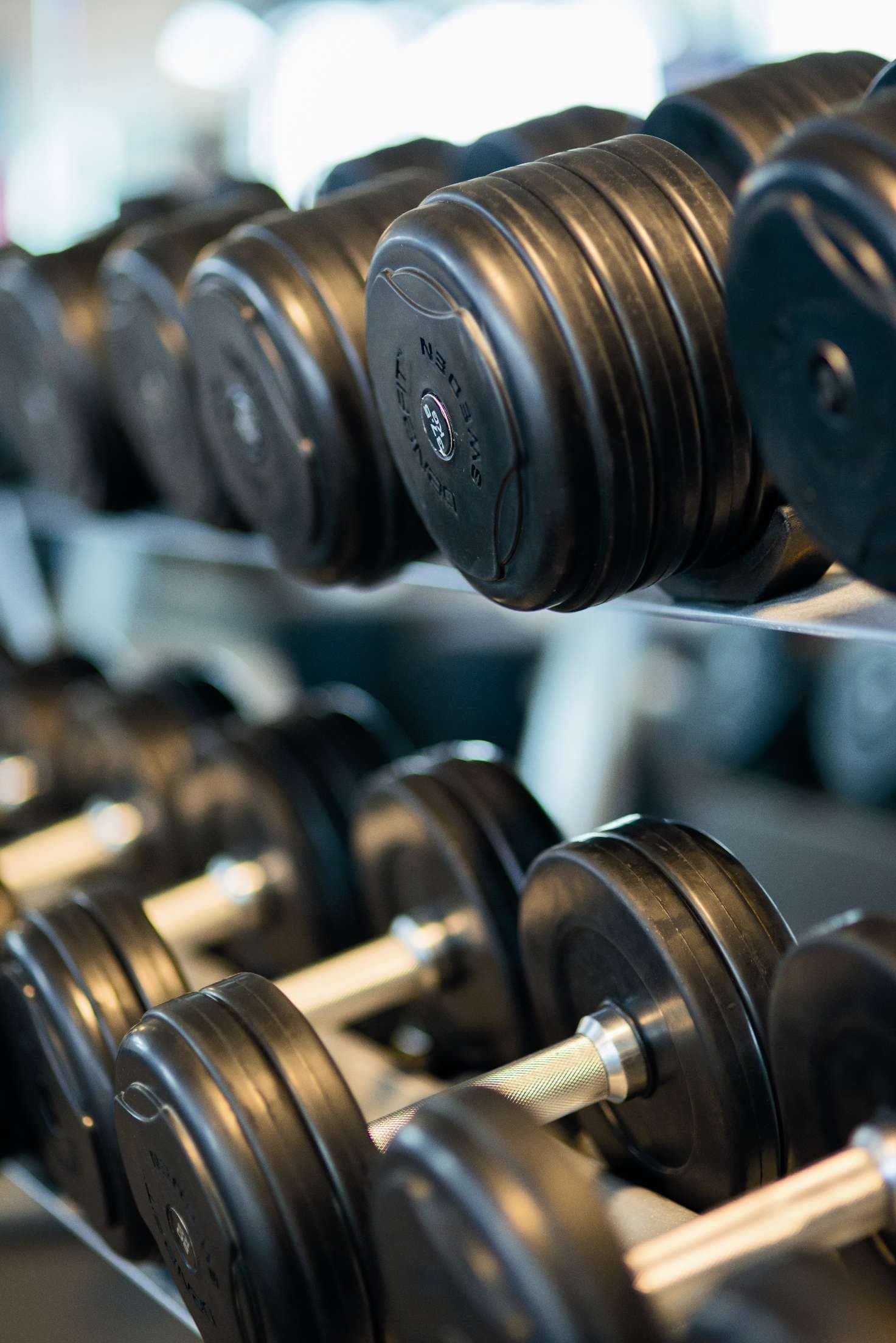 A picture of a gym with weights and a bench press in the background.